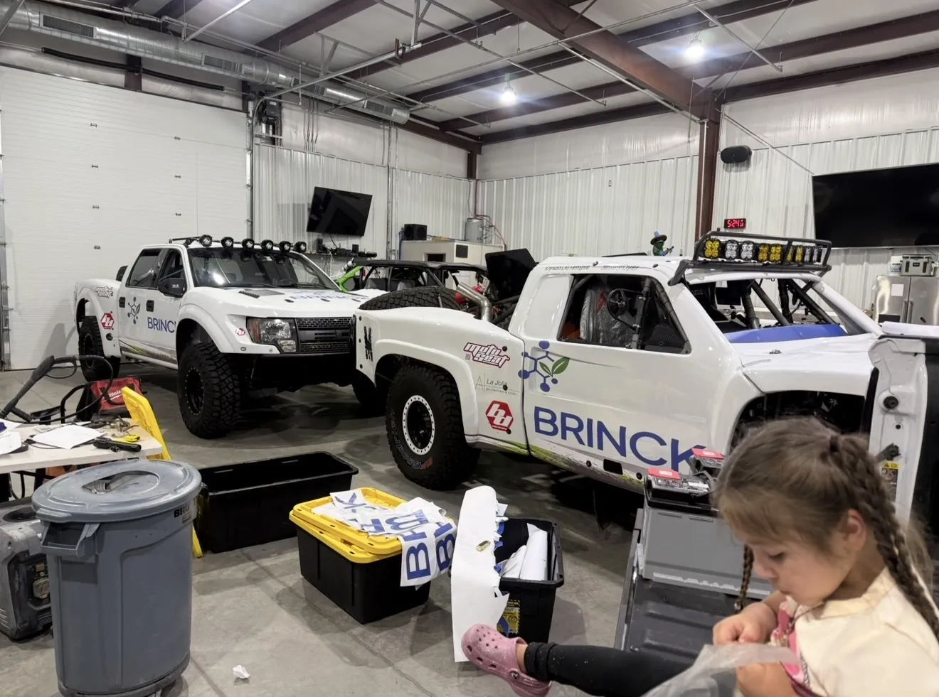 WrappStarr wrap job in progress on Brinck off-road race trucks, with Brian's daughter helping in the shop